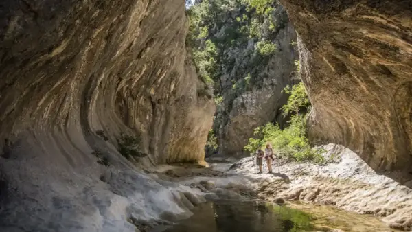 Deux randonneurs explorent les formations rocheuses spectaculaires des concluses de Lussan, un paysage naturel impressionnant.