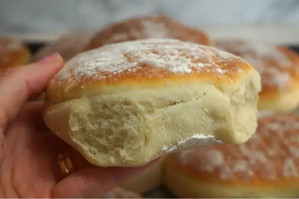 En hand håller en nybakad tekaka, pudrad med mjöl. Perfekt för ett enkelt tekakor recept.