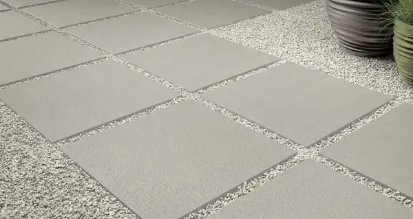 Posa a secco su ghiaia: lastre quadrate grigie alternate a ghiaietto bianco creano un percorso moderno e pulito.