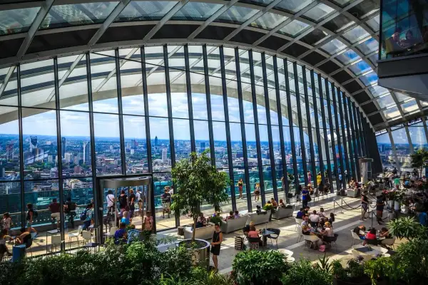 Relaks w Sky Garden w Londynie. Ludzie odpoczywają wśród zieleni, podziwiając panoramę miasta przez szklany dach.