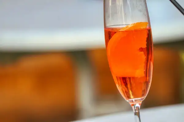 Orzeźwiający lillet drink z plasterkiem pomarańczy w kieliszku, gotowy na letnie popołudnie.