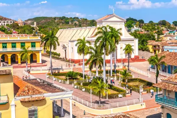 Plaza de Trinidad, Cuba. Un lugar perfecto para planear cuando viajar a Cuba, con su iglesia blanca, casas coloniales y palmeras.