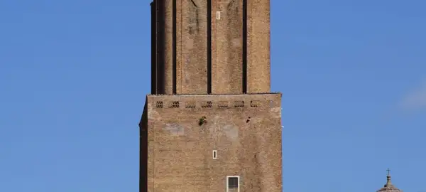 La torre delle Milizie, imponente struttura in mattoni, si staglia contro un cielo azzurro.