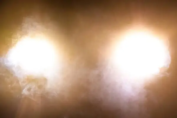 Deux halos lumineux, couleur feu de croisement, traversent une brume légère.