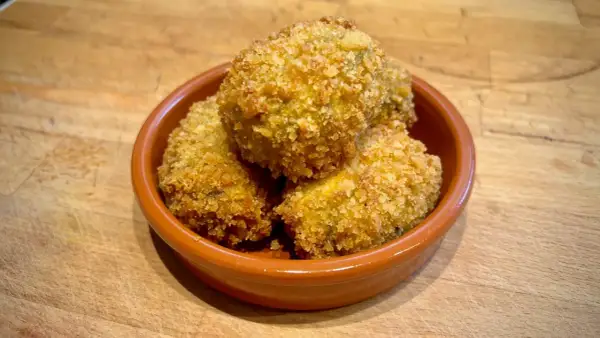 Goldbraune spanische Kroketten, knusprig paniert, in einer Tonschale. Ein leckeres spanische kroketten rezept zum Genießen.