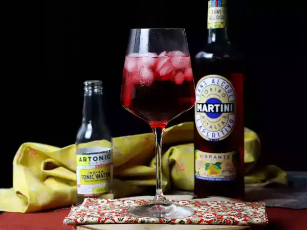 Czerwony drink z lodem, obok butelka Martini Vibrante i Artonic Indian Tonic Water. Idealny na letnie popołudnie.