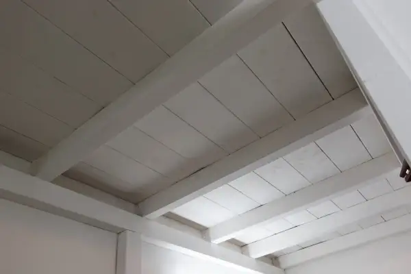 Deckenbalken und Holzpaneele, frisch weiß gestrichen, erhellen den Raum.