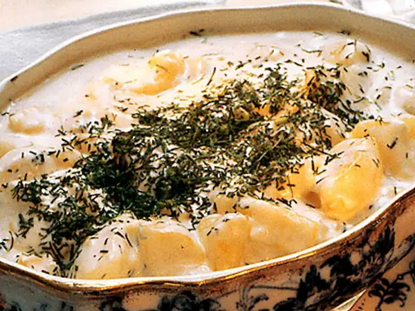 En krämig stuvad potatis med dill, serverad i ett vackert fat. En klassisk svensk rätt som värmer själen.