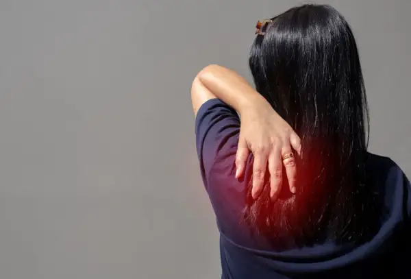 Douleur au muscle omoplate, une main masse la zone rouge sur le dos d'une femme.