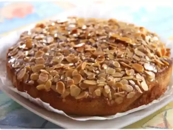 Gâteau aux amandes, doré et croustillant, garni de lamelles d'amandes grillées sur un glaçage brillant.