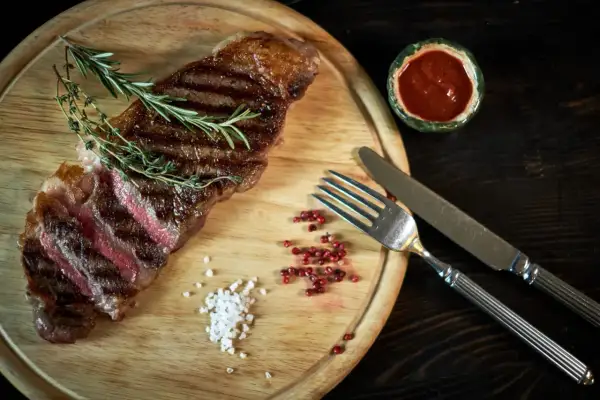 Succulenta bistecca di manzo, uno dei tanti tipi di bistecche di manzo, servita con rosmarino, sale grosso e pepe rosa.
