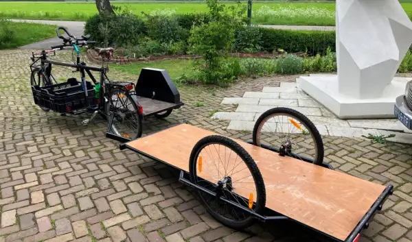 Een fiets met een bakfiets-achtige constructie en een aanhanger, klaar om een zijspan fiets te maken.