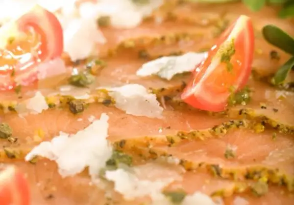 Pyszne carpaccio z łososia z pomidorkami, parmezanem i zielonym sosem do carpaccio.