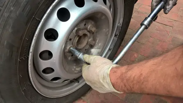Main tenant utilise une clé pour changer un pneu.