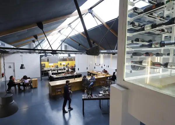 Interior de un restaurante con cocina abierta y estanterías de vino. Un lugar ideal para disfrutar de una experiencia Bib Gourmand en Zaragoza.
