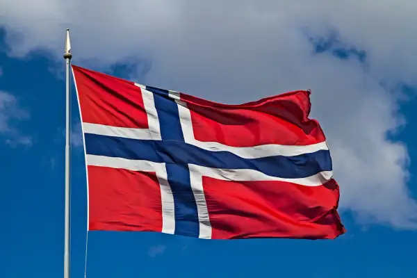 Norwegia praca dla kobiet: flaga powiewa na tle błękitnego nieba z chmurami.