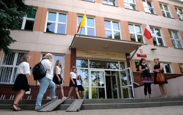 Uczniowie wchodzą do szkoły, przypominając czasy, kiedy powstały gimnazja w Polsce.