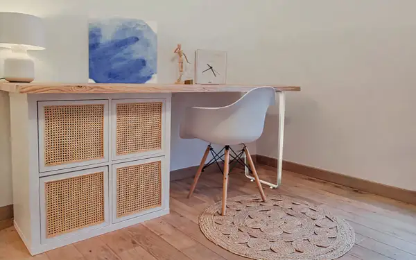 Bureau en pin relooké avec des portes en rotin. Une chaise blanche et un tapis rond complètent ce coin bureau moderne.