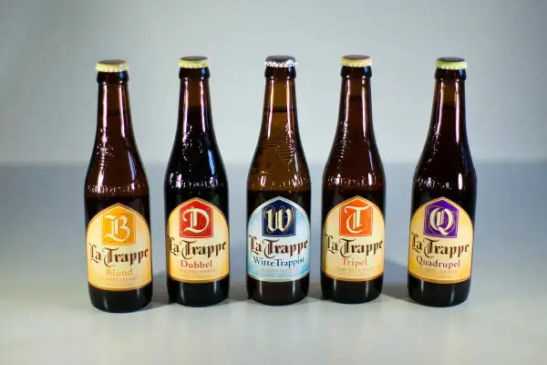 Cinque bottiglie di birra La Trappe, tra cui Blond, Dubbel, Witte Trappist, Tripel e Quadrupel, disposte in fila.