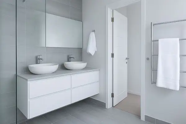 Modernos lavabos dobles sobre mueble blanco, espejo grande y azulejos grises. ¡Ideas para reformas de baños elegantes y funcionales!