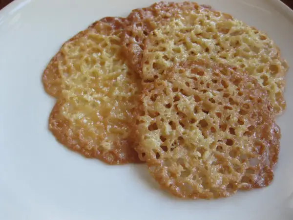 Tre gyllene havreflarn ligger på en vit tallrik. Dessa spröda kakor är perfekta för ett enkelt havreflarn recept.