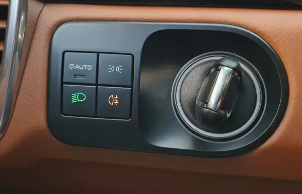Panel sterowania w Oplu Astra H. Przyciski do świateł: AUTO, mijania, przeciwmgielne (tylne pomarańczowe).