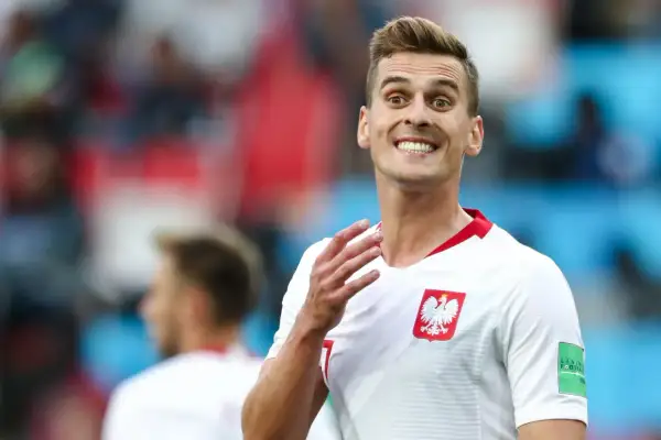 Piłkarz reprezentacji Polski z szerokim uśmiechem, jakby cieszył się z każdego wieku sukcesu. Biała koszulka z godłem orła.