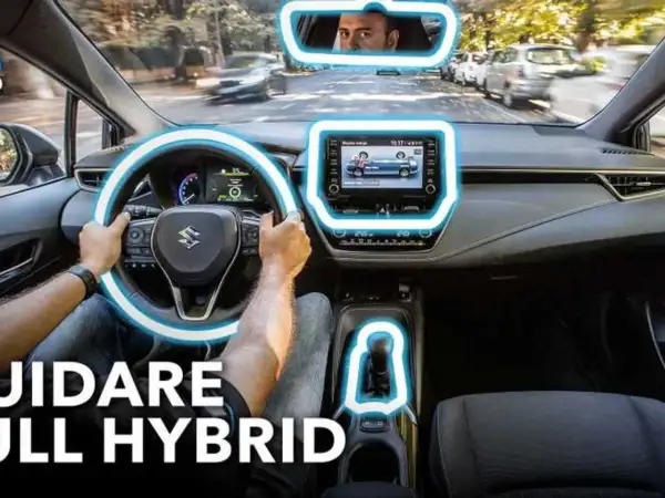 Interno di un'auto ibrida, con le mani sul volante e il display centrale acceso. Scopri il significato di auto ibrida e guida in modo ecologico.