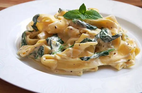 Pappardelle w kremowym sosie ze szpinakiem i mascarpone, udekorowane listkami mięty. Pyszne danie, które zachwyci każdego.