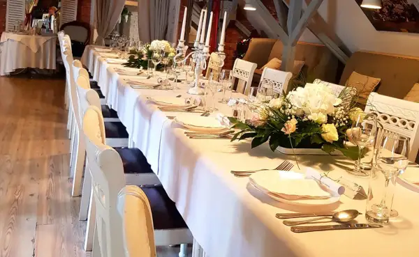 Elegancko nakryty stół w restauracji, gotowy na przyjęcie. Zastanawiasz się, ile trwają chrzciny w restauracji? Zazwyczaj to kilka godzin, w zależności od programu.