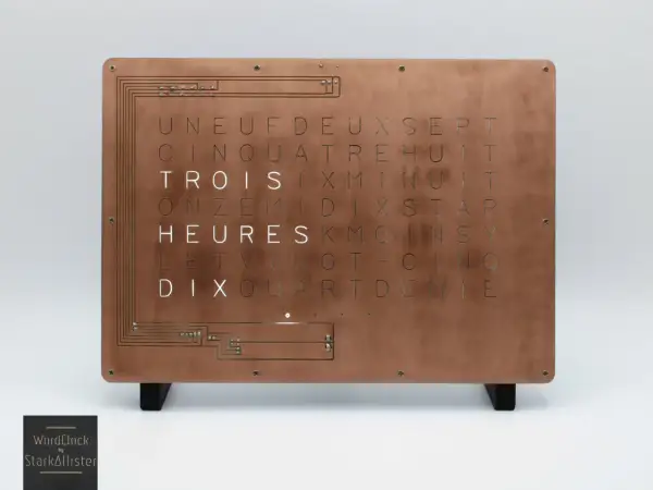 Horloge murale au design industriel, avec une plaque de cuivre gravée de lettres formant des mots. Une lettre métal unique pour un style épuré.