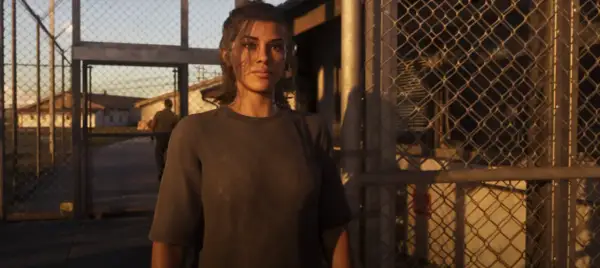 Lucia z GTA 6 stoi przed bramą, za nią widać budynki i strażnika.
