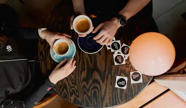 Dwie osoby przy stoliku piją kawę. Rozmowa o autofagii i dobrej kawie przy filiżankach espresso.