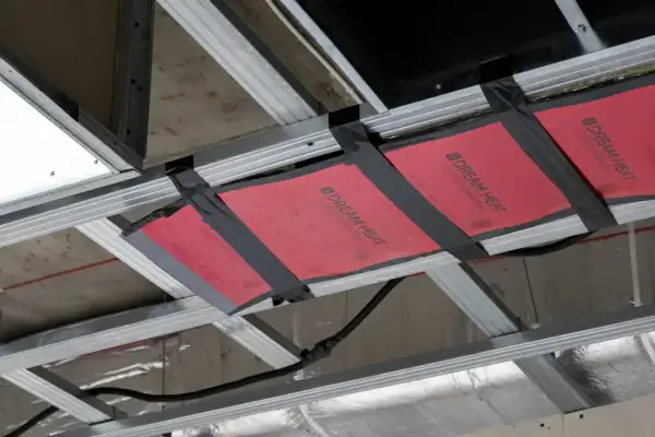 Instalacja grzejnika na podczerwień w suficie podwieszanym. Wady montażu widoczne na taśmie mocującej.