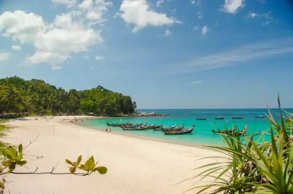 Piękne phuket plaże z turkusową wodą, białym piaskiem i łodziami dryfującymi na morzu.