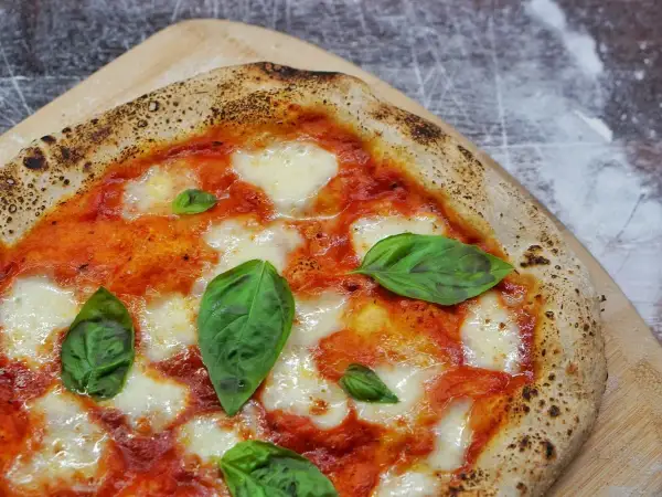 Une Margherita parfaite, symbole de la recette pizza italienne traditionnelle. Sauce tomate, mozzarella fondante et basilic frais sur une pâte dorée.