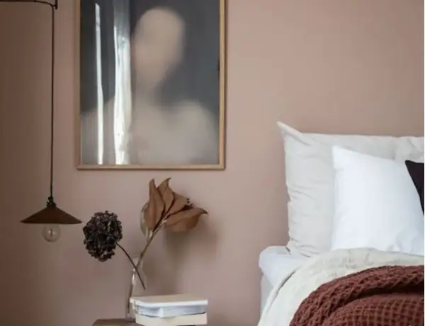 Un angolo letto con pareti color malva, un quadro astratto e un vaso con fiori secchi. Gli abbinamenti verde malva colore creano un'atmosfera rilassante.
