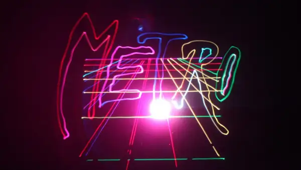 Kolorowe, neonowe linie tworzą napis "METRO" na czarnym tle, przypominając o energetycznym, musical metro.