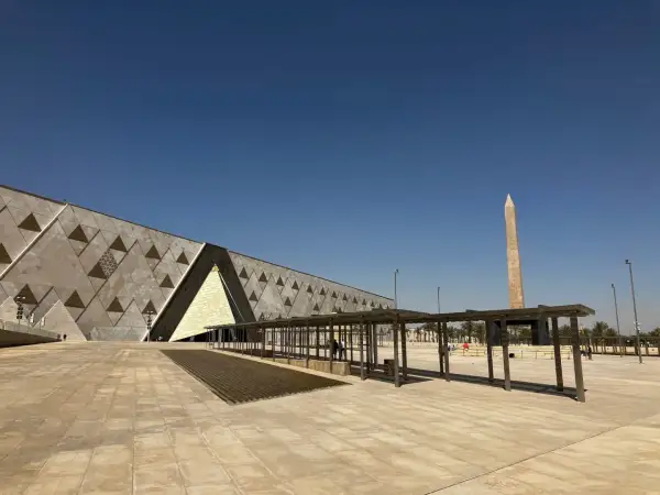 Nowoczesne muzeum egipskie z obeliskiem w tle, pod błękitnym niebem.