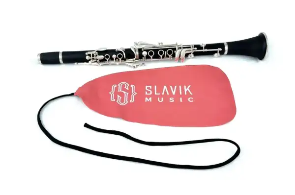 Elegancki klarnet leży obok różowego pokrowca z logo Slavik Music. Obój i klarnet to instrumenty dęte drewniane.