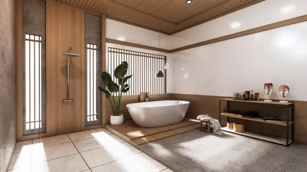 Minimalistyczna łazienka japandi z wolnostojącą wanną, drewnianymi elementami i kamiennymi detalami.
