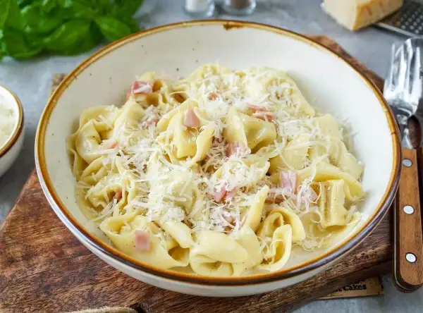 Schon gewusst? Tortellini einfrieren ist eine tolle Idee, um sie später zu genießen. Hier sind sie mit Schinken und Parmesan serviert.