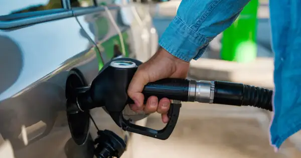 Dłoń trzymająca pistolet paliwowy przy samochodzie. Czas na zimowe paliwo od kiedy? Przygotuj auto na mrozy.