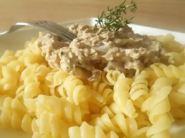 Pâtes fusilli généreusement garnies d'une sauce crémeuse aux pâtes au thon, décorées d'une branche de thym.