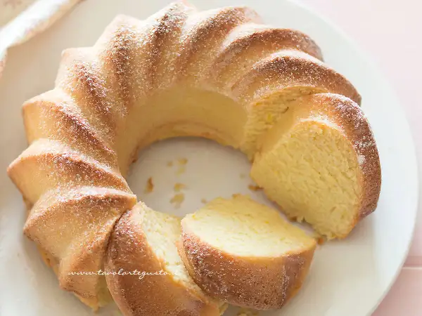 Una soffice torta di ricotta, spolverata di zucchero a velo, con una fetta tagliata che ne rivela la morbidezza.