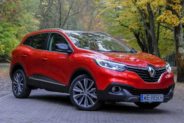 Czerwony Renault Kadjar na tle jesiennego lasu. Wady tego modelu to m.in. przeciętne wyciszenie i twarde zawieszenie.