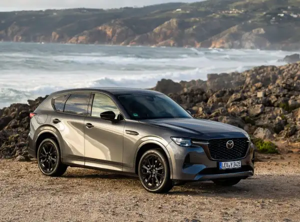 Szary SUV Mazda CX-60 na tle skalistego wybrzeża. To jeden z rodzajów hybryd, który łączy moc z ekologią.