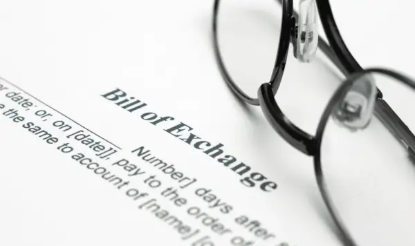Okulary leżą na dokumencie "Bill of Exchange". To jest weksel, czyli papier wartościowy, który zobowiązuje do zapłaty określonej sumy pieniędzy.