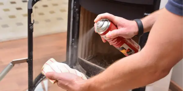 Hände reinigen den Kamin: Mit einem Reiniger wird der Ruß vom Schamottstein und Glas entfernt.