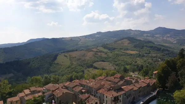 Panoramica di un borgo con tetti in cotto e colline verdi. Un assaggio di cosa vedere sul Monte Amiata, tra natura e storia.